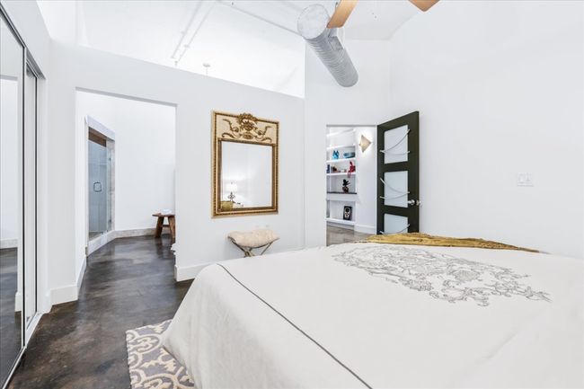 Bedroom with a high ceiling, finished stained concrete flooring, open to primary bath and ceiling fan | Image 29