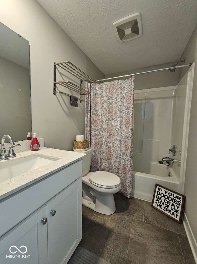 full bathroom featuring vanity, toilet, shower / bath combo, and a textured ceiling | Image 25