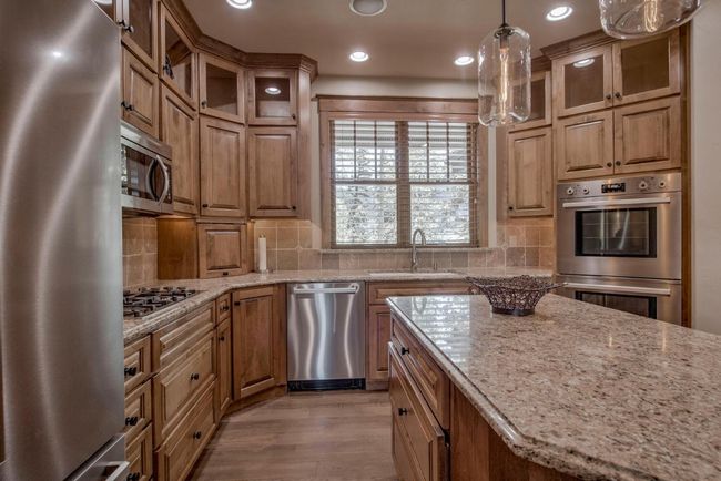 Kitchen with stainless steel appliances, an island, and kitchen desk area. | Image 10