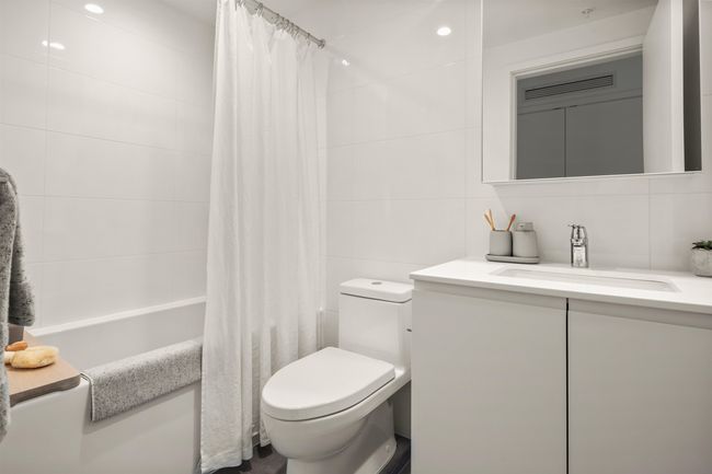 Bathroom with tile walls, vanity, shower / bath combination with curtain, and toilet | Image 6