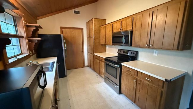 Kitchen with wood ceiling, brown cabinets, visible vents, stainless steel appliances, and vaulted ceiling | Image 19