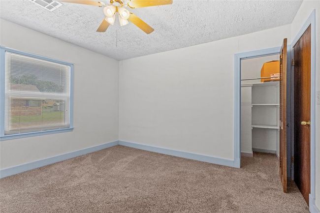 Unfurnished bedroom with ceiling fan, carpet floors, and a textured ceiling | Image 15