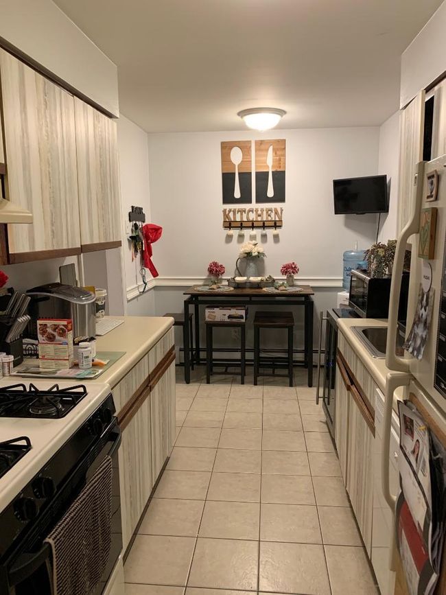 Eat in kitchen featuring lots of cabinets and a pretty ceramic tile floor, a refrigerator, gas range and dishwasher | Image 6