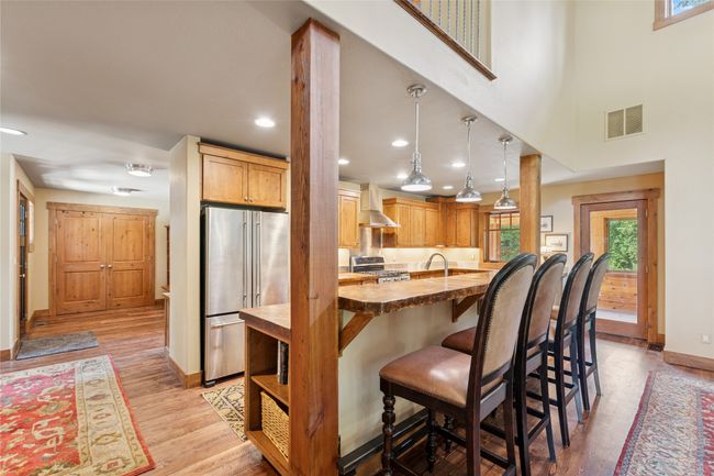 Kitchen featuring appliances with stainless steel finishes, wall chimney range hood, a breakfast bar, light wood-type flooring, and recessed lighting | Image 21