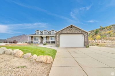 View of front of home with a front yard, a garage, a mountain view, and a porch | Image 1