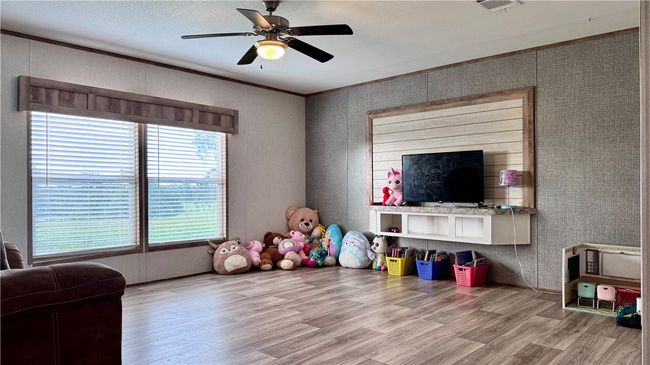 Recreation room featuring wood finished floors, ceiling fan, and ornamental molding | Image 15