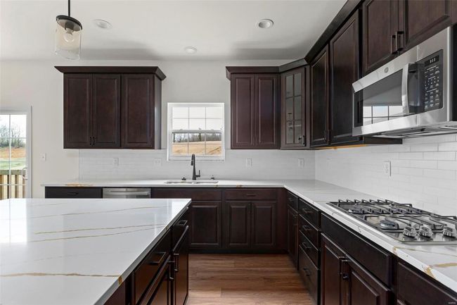 Kitchen featuring decorative backsplash, dark hardwood / wood-style flooring, dark brown cabinetry, stainless steel appliances, and sink | Image 21