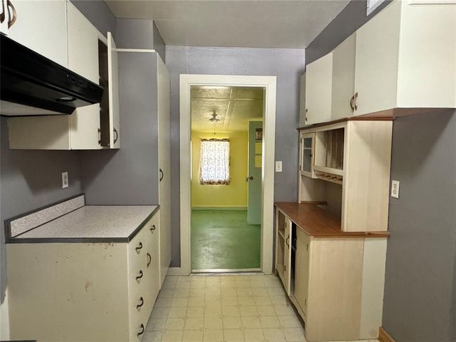 Kitchen with fume extractor, white cabinets, and light tile flooring | Image 20