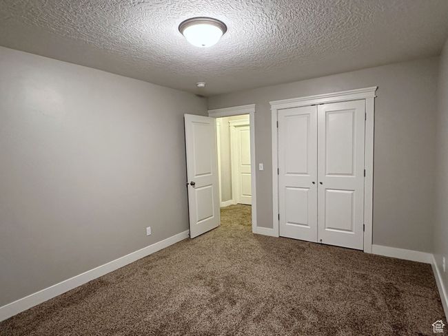 Unfurnished bedroom with carpet flooring, a textured ceiling, and a closet | Image 18
