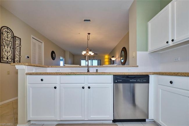 Kitchen featuring tasteful backsplash, a notable chandelier, white cabinets, visible vents, and stainless steel dishwasher | Image 22