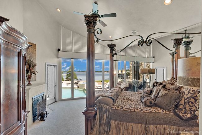 Bedroom with carpet, a water view, a high ceiling, and a glass covered fireplace | Image 24