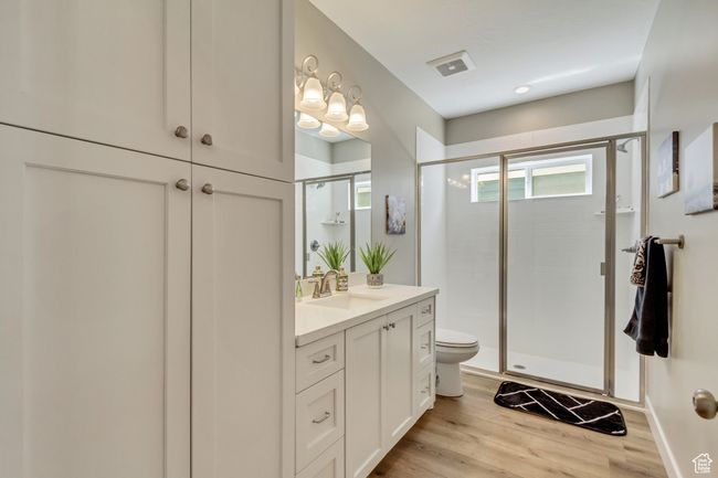 Bathroom featuring toilet, visible vents, wood finished floors, a shower stall, and vanity | Image 23