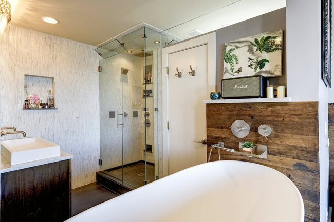 Bathroom with a stall shower, a freestanding tub, wood finished floors, double vanity, and wallpapered walls | Image 8