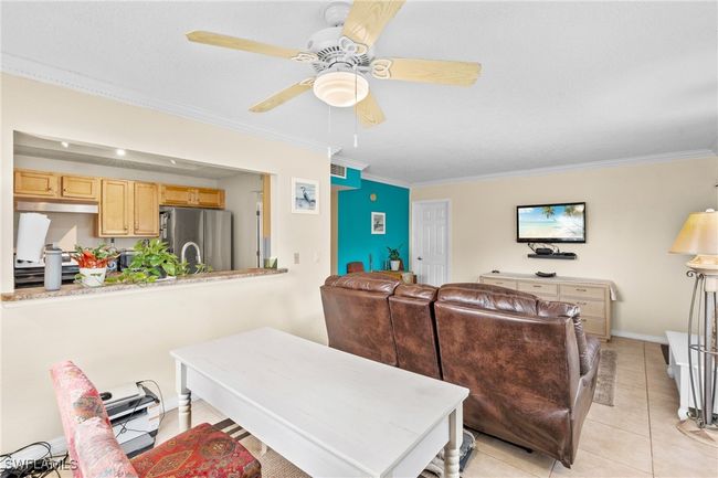Living area featuring light tile patterned floors, baseboards, crown molding, and a ceiling fan | Image 8