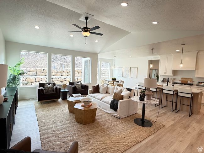 Living room with light wood-type flooring, vaulted ceiling, a textured ceiling, and recessed lighting | Image 4