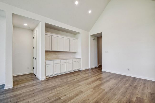 Empty room with light wood finished floors, high vaulted ceiling, and recessed lighting | Image 21