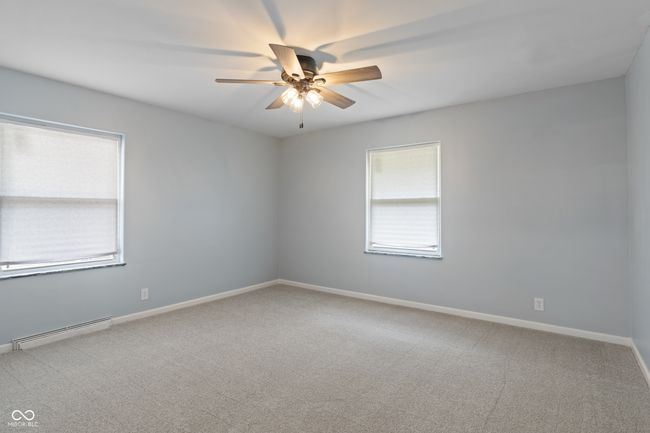 empty room with a baseboard radiator, ceiling fan, carpet floors, and baseboards | Image 30