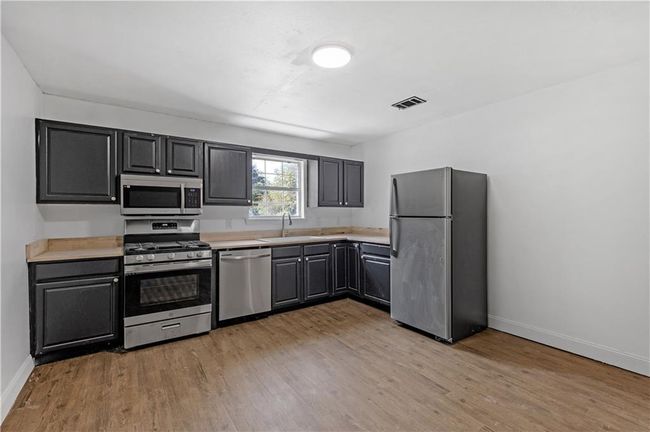 Kitchen with visible vents, baseboards, light countertops, light wood-style flooring, and stainless steel appliances | Image 7