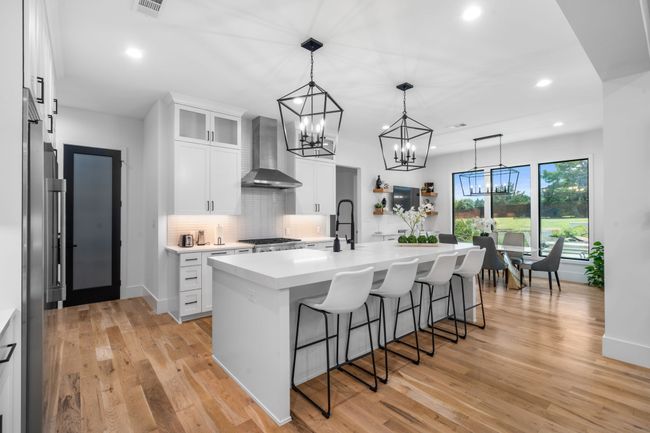 Kitchen with wall chimney exhaust hood, a kitchen breakfast bar, recessed lighting, light countertops, and a chandelier | Image 10