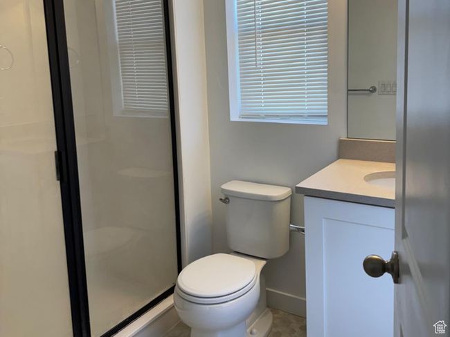 Bathroom featuring tile patterned floors, a shower stall, toilet, vanity, and baseboards | Image 7