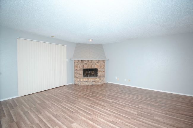 Unfurnished living room with a textured ceiling, a fireplace, and light hardwood / wood-style flooring | Image 12