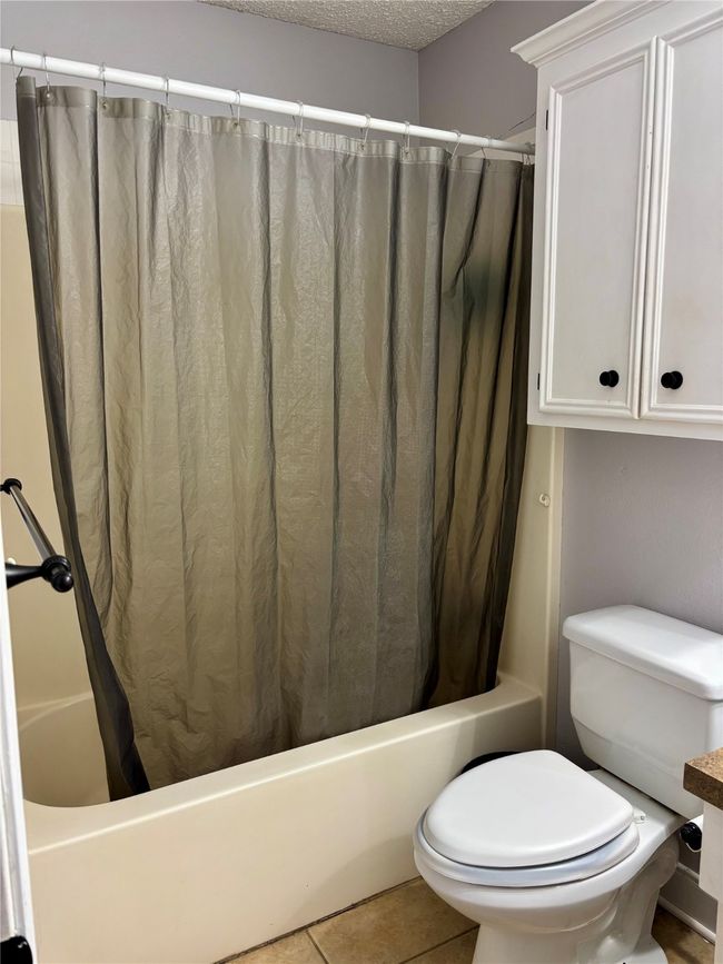 Full bathroom with shower / bath combination with curtain, tile patterned flooring, and a textured ceiling | Image 15