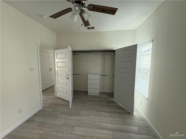 Unfurnished bedroom with wood finished floors, a closet, baseboards, and ceiling fan | Image 13