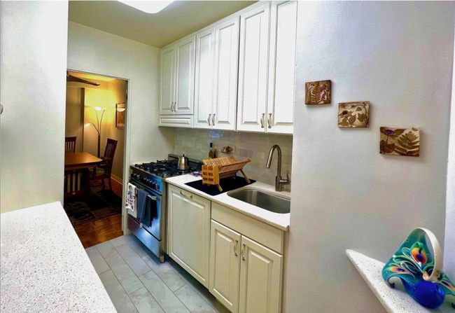 Kitchen with stainless steel stove, light countertops, tasteful backsplash, and white cabinetry | Image 5