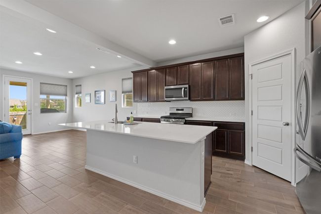The charming kitchen boasts a large center island/breakfast bar, a pantry, and is open to the dining area making cooking meals the focal point of the home | Image 7