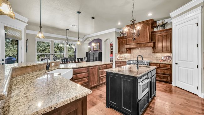 Kitchen with a chandelier, arched walkways, recessed lighting, brown cabinetry, and decorative backsplash | Image 18