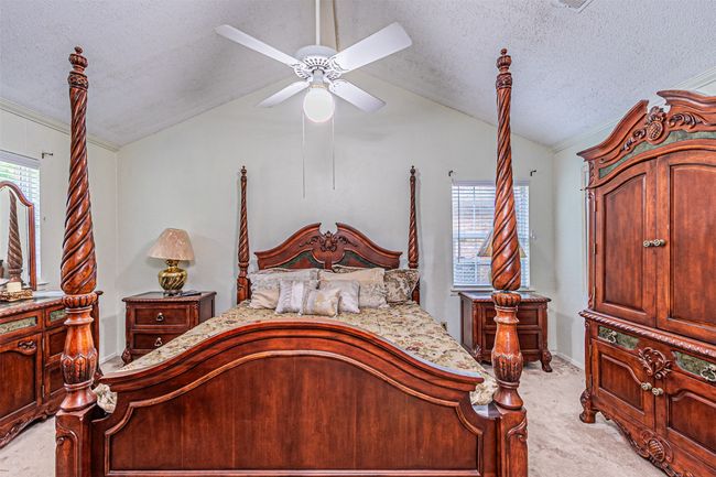 Bedroom with light colored carpet, ceiling fan, baseboards, a textured ceiling, and lofted ceiling | Image 15