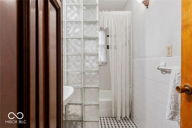 bathroom with tile walls, shower / bathtub combination with curtain, a wainscoted wall, and tile patterned floors | Image 33