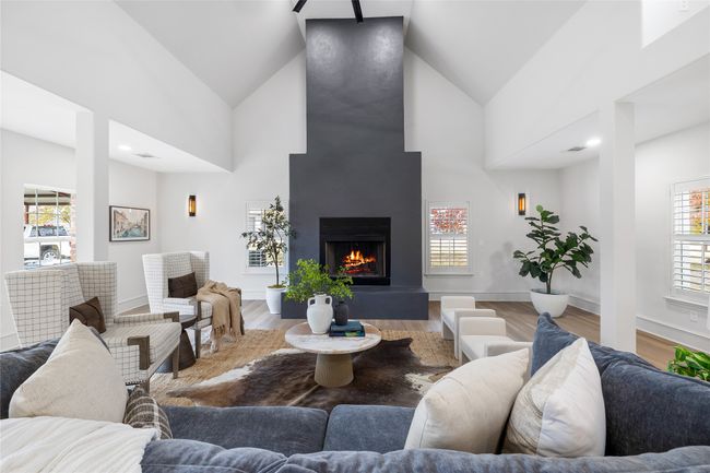 Living area with healthy amount of natural light, a warm lit fireplace, high vaulted ceiling, and wood finished floors | Image 21