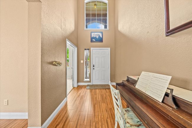 Foyer with baseboards, wood finished floors, a textured wall, and a towering ceiling | Image 4