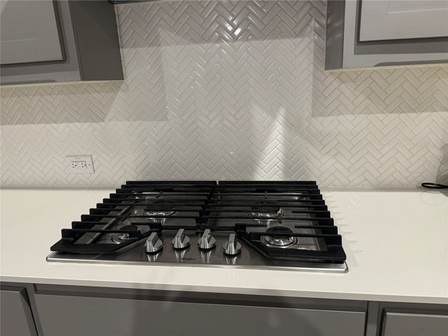 Room details with decorative backsplash, gray cabinets, and gas cooktop | Image 13