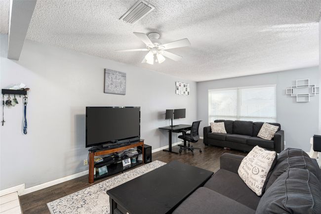 Living room with dark wood-type flooring, ceiling fan | Image 5