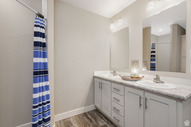 Bathroom with baseboards, wood finished floors, double vanity, and a shower with shower curtain | Image 9