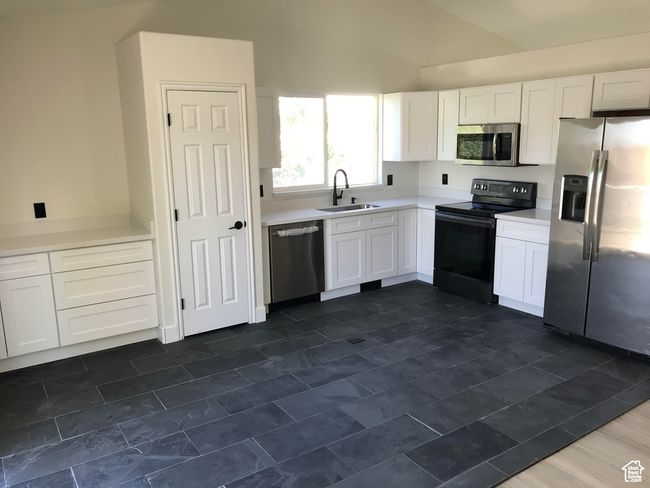 Kitchen featuring appliances with stainless steel finishes, white cabinetry, light countertops, and high vaulted ceiling | Image 5