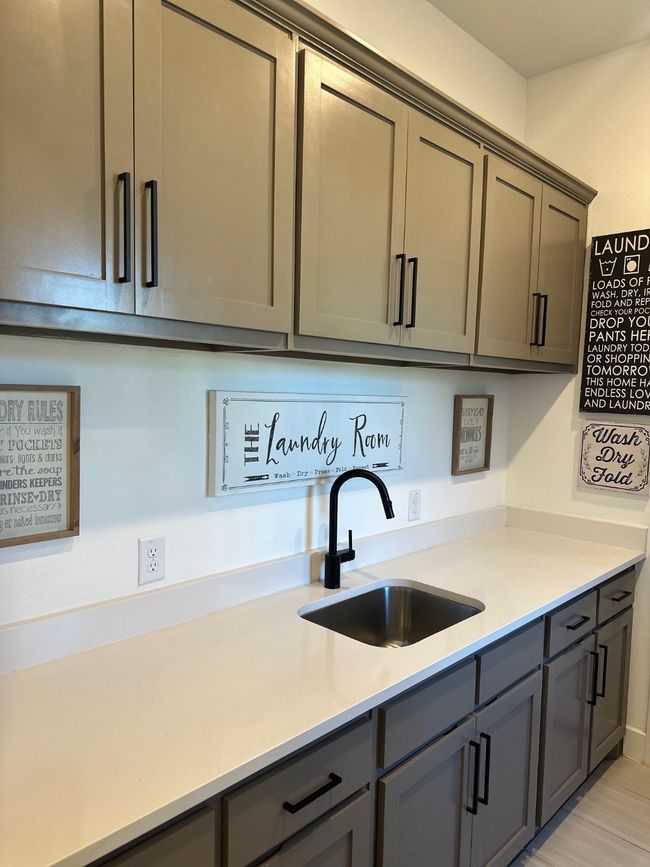Kitchen with gray cabinets, light countertops, and a sink | Image 30