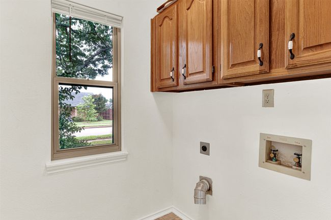 Laundry area featuring electric dryer hookup, cabinet space, and hookup for a washing machine | Image 34