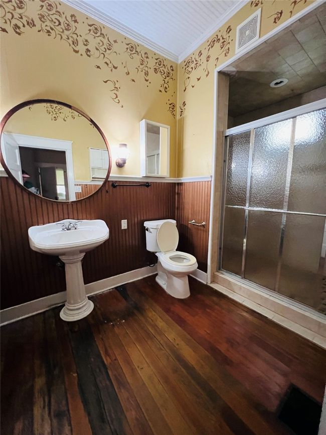 Full bath with a wainscoted wall, hardwood / wood-style flooring, ornamental molding, and a stall shower | Image 12