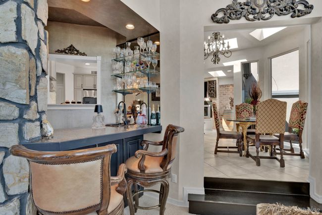 Bar featuring light tile patterned floors, a notable chandelier, baseboards, and bar area | Image 9