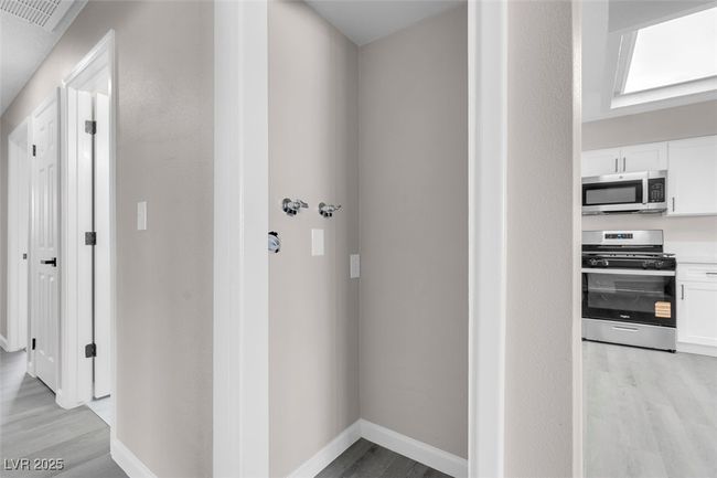 Hallway with light wood-style floors, visible vents, and baseboards | Image 32