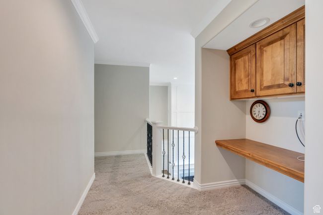 Hall with carpet, baseboards, crown molding, and a desk | Image 26