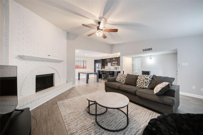 Living area with ceiling fan, wood finished floors, and a fireplace | Image 5