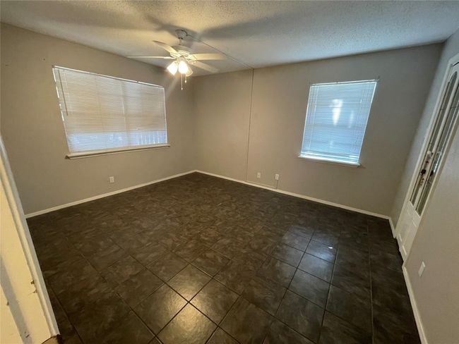 Empty room with ceiling fan and a textured ceiling | Image 4