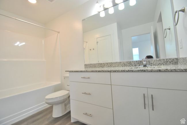 Main Bathroom featuring wood finished floors, vanity, and tub / shower combination | Image 9
