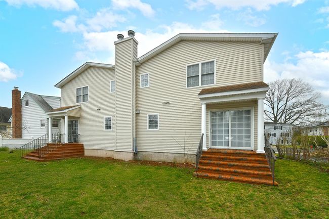 Back of house featuring a yard, a chimney, and entry steps | Image 23