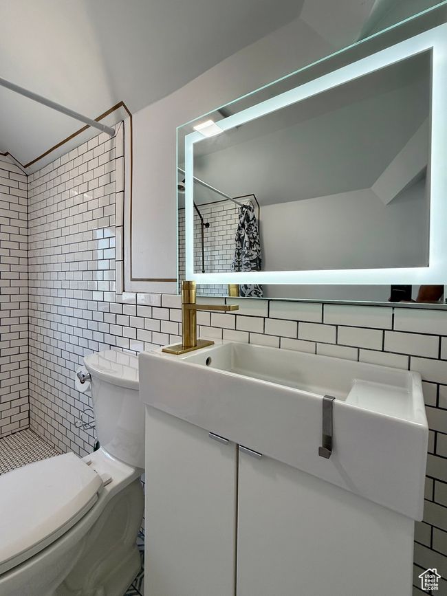 Bathroom featuring tile walls, a tile shower, toilet, vanity, and decorative backsplash | Image 30