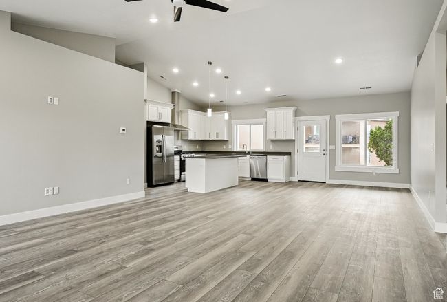 Unfurnished living room with ceiling fan, plenty of natural light, light wood-style floors, recessed lighting, and high vaulted ceiling | Image 12
